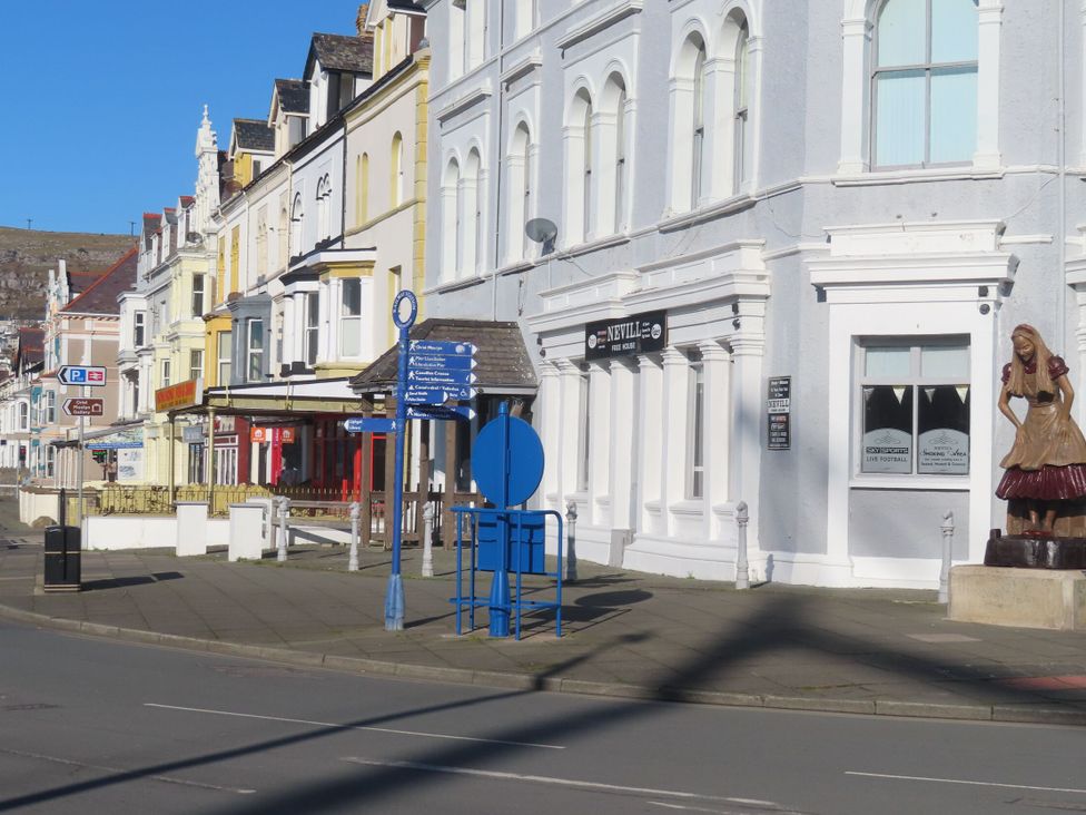 Street view with shops and a sculpture at The Causeway in Llandudno