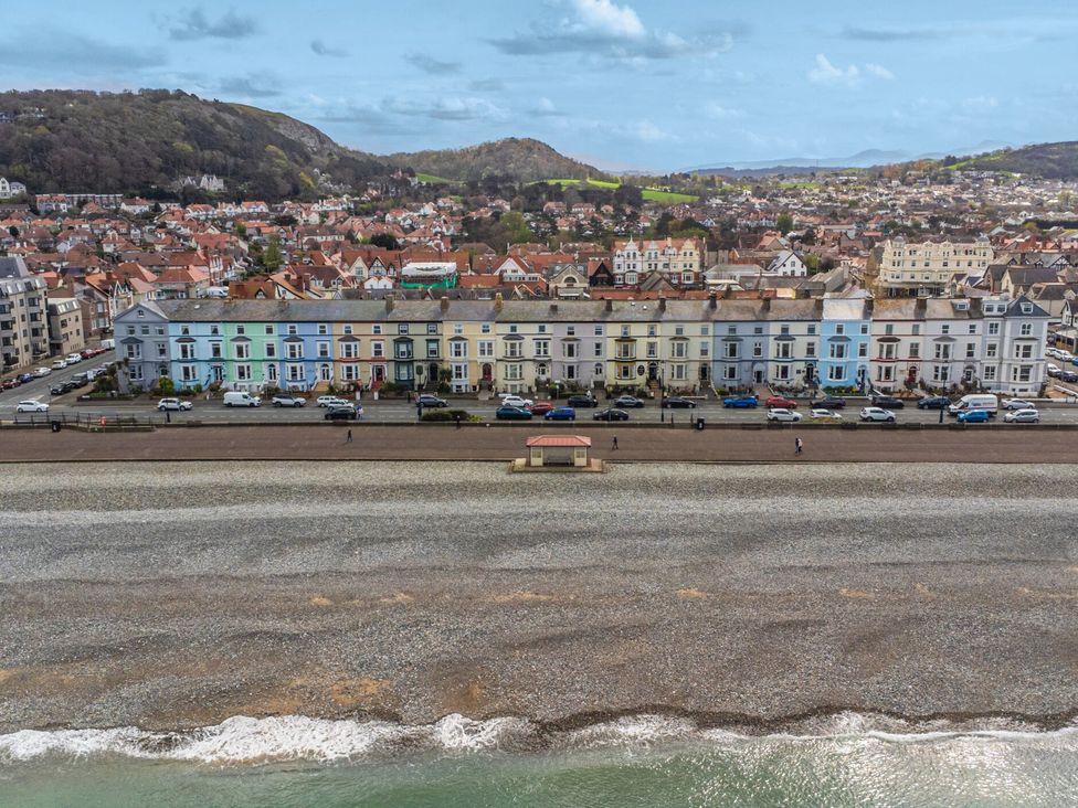 A beach with houses and cars along the promenade at The Causeway in Llandudno