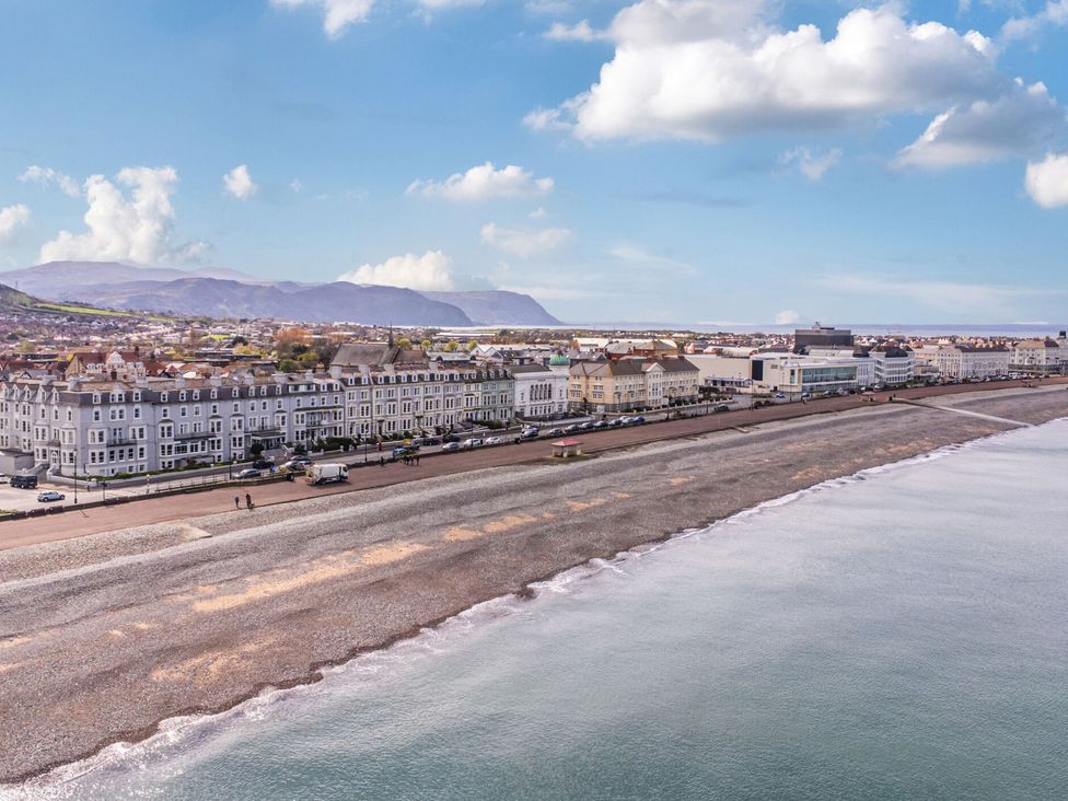 A beach with pebbles and buildings along a promenade at The Causeway in Llandudno