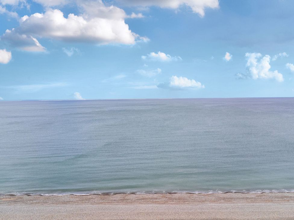 A beach with sand and ocean under a blue sky at The Causeway in Llandudno