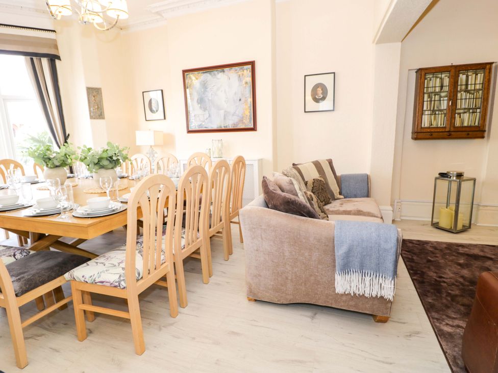 A dining room with a table set for dinner and a sofa at The Causeway Llandudno