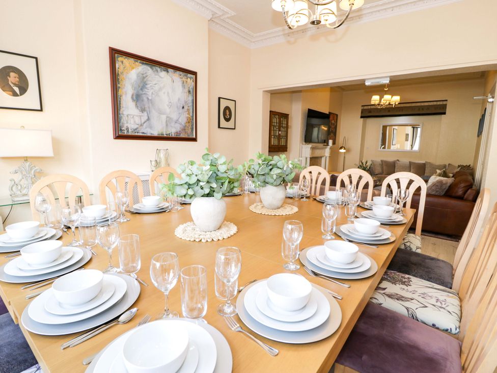 A dining room with a large table set for dinner at The Causeway in Llandudno