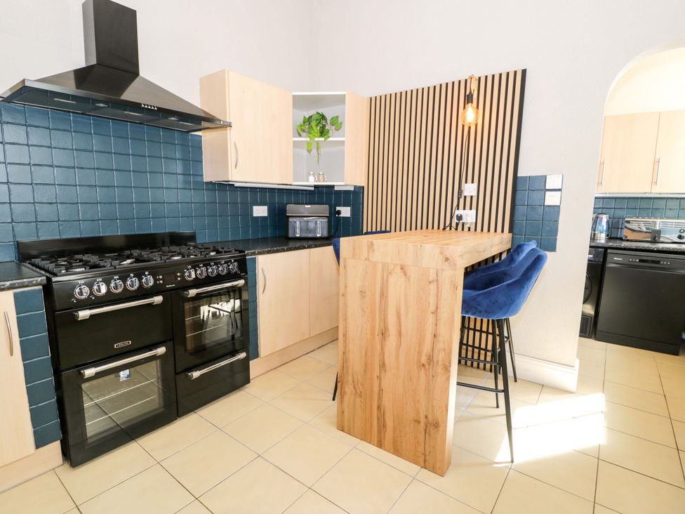 A kitchen with oven, counter, and bar stools at The Causeway in Llandudno