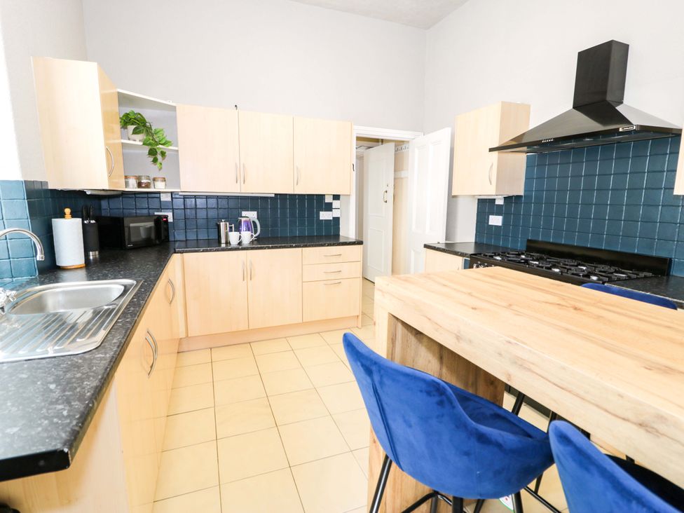 A kitchen with wooden cabinets and a breakfast bar at The Causeway in Llandudno