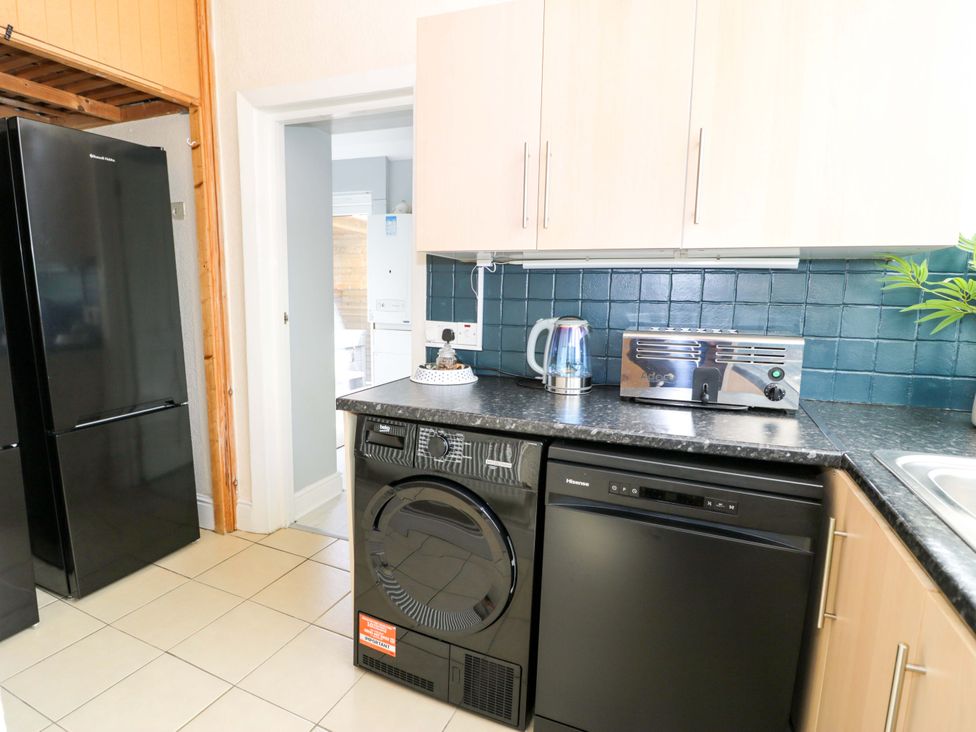A kitchen with refrigerator, washing machine, and kettle at The Causeway in Llandudno