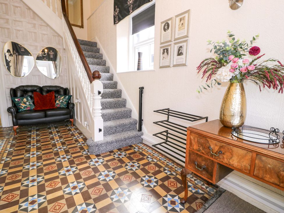 A hallway with a staircase, sofa, and console table at The Causeway in Llandudno