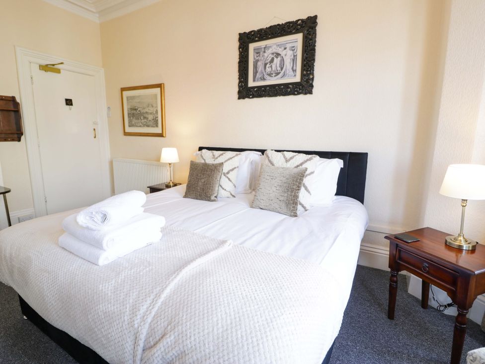 A bedroom with a bed, towels, lamp and wall art at The Causeway in Llandudno