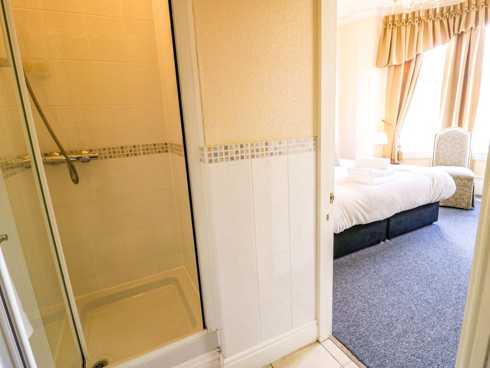 A bathroom with a shower and bed visible at The Causeway in Llandudno