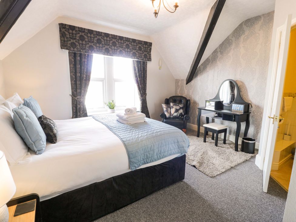 A bedroom with a bed, desk, chair and window at The Causeway in Llandudno