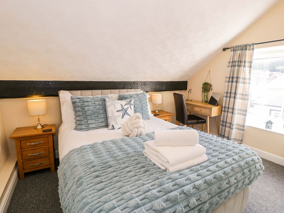 A bedroom with a bed, bedside table, and desk at The Causeway in Llandudno