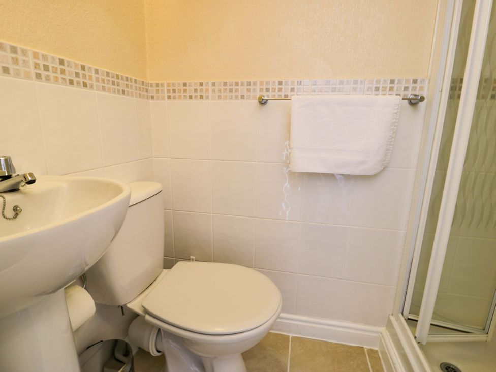 A bathroom with a sink, toilet, towel, and shower at The Causeway in Llandudno