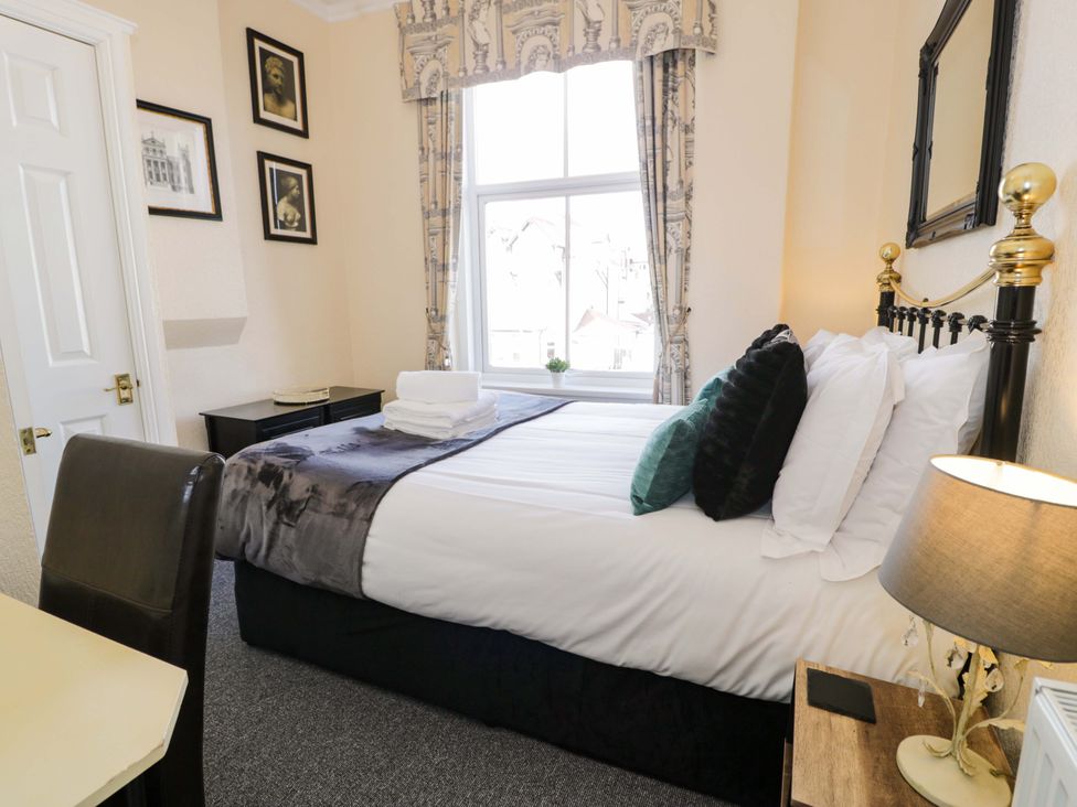 A bedroom with a bed, desk, chair, and window at The Causeway in Llandudno