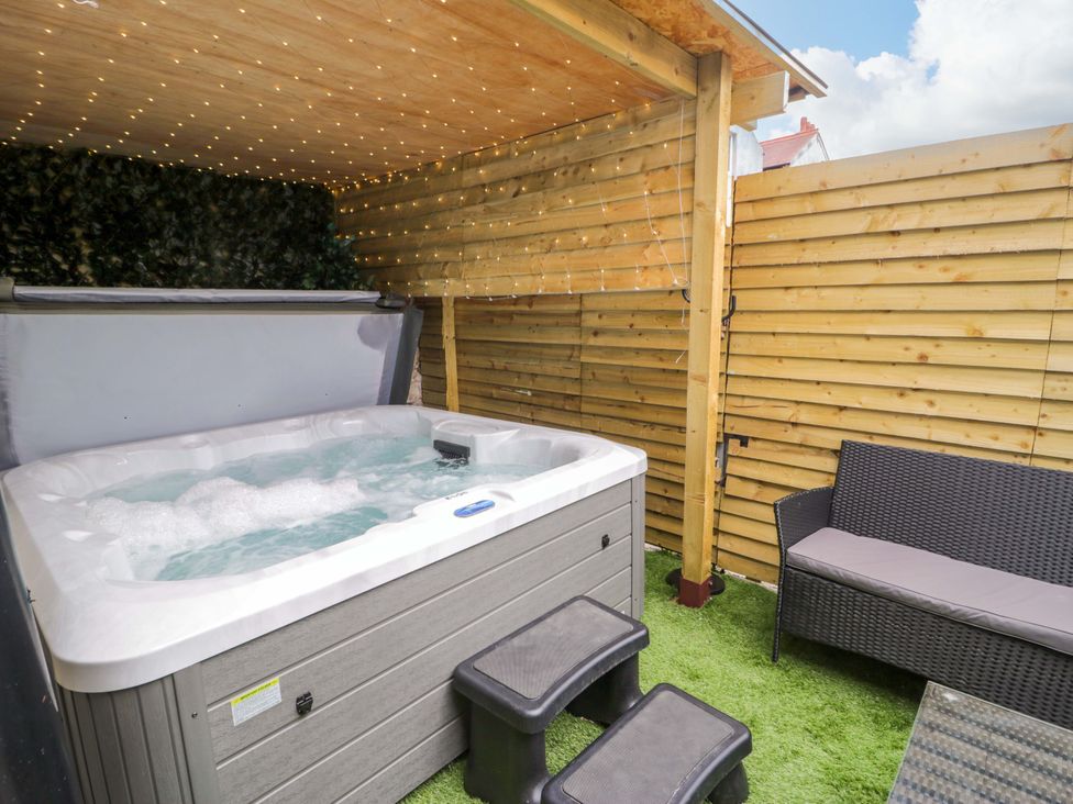 A hot tub with seating area and wooden fence at The Causeway in Llandudno