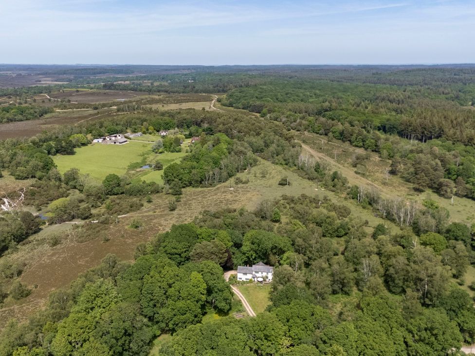 An aerial view of a house surrounded by trees and fields at Primrose Spinney in Highwood near Ringwood