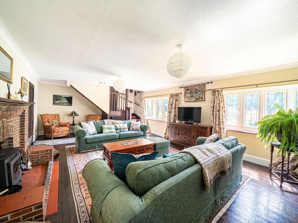 A living room with green sofas and a fireplace at Primrose Spinney in Highwood near Ringwood