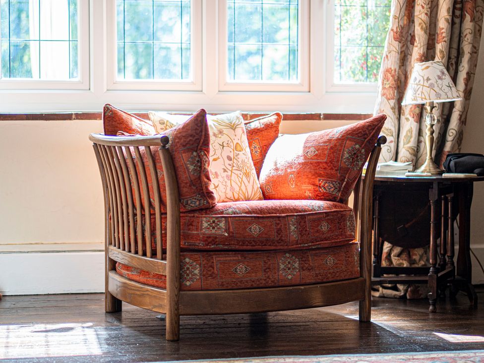 A chair with cushions near a window at Primrose Spinney Highwood near Ringwood