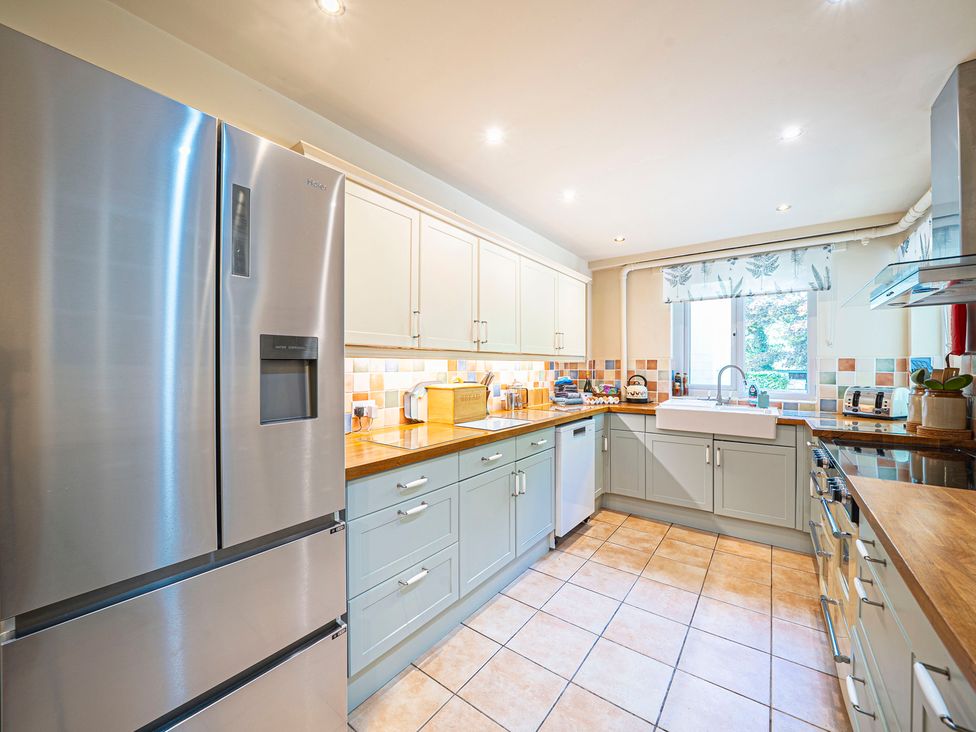 A kitchen with a refrigerator, sink, and countertop at Primrose Spinney Highwood near Ringwood