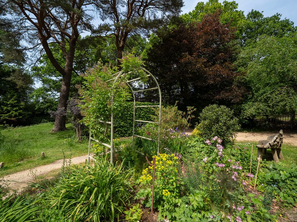 A garden with a flower bed and archway at Primrose Spinney Highwood near Ringwood