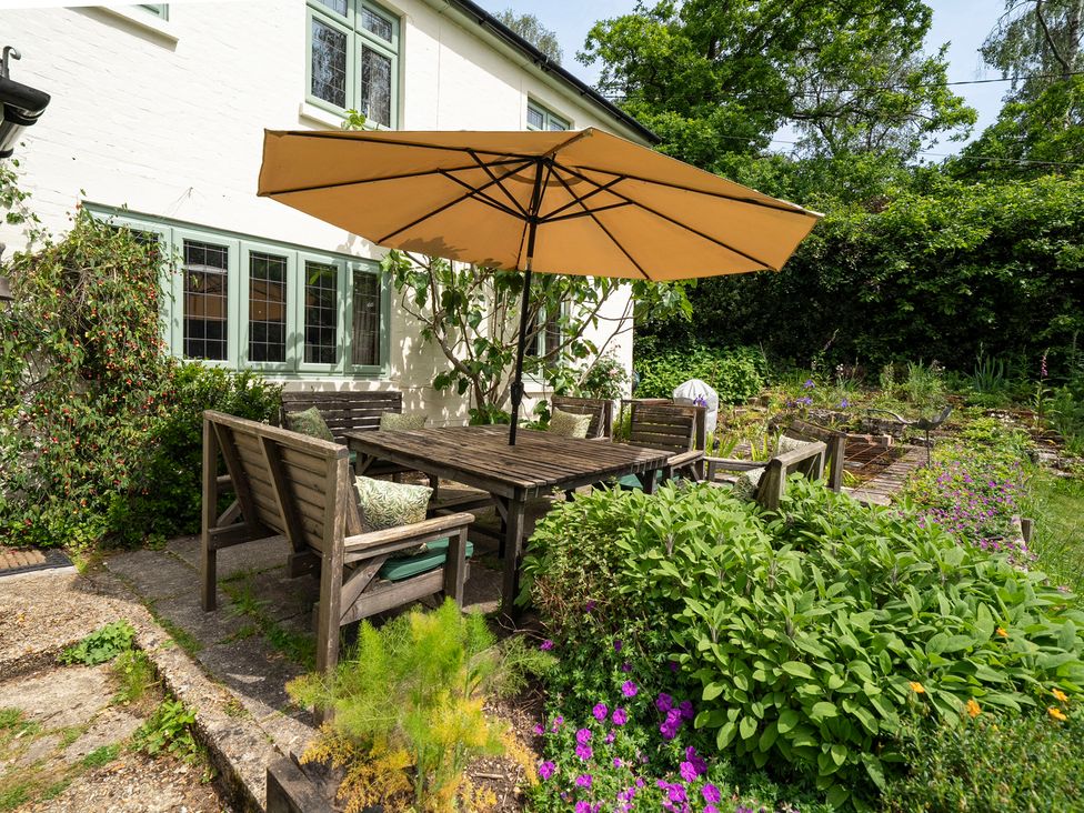 A garden with dining table and umbrella at Primrose Spinney in Highwood near Ringwood