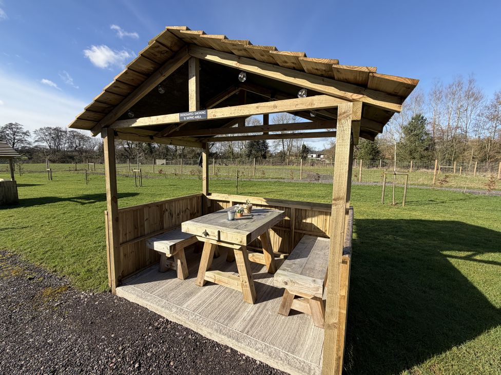 An outdoor seating area with a wooden gazebo and picnic table at Oh Deer in Ashbourne
