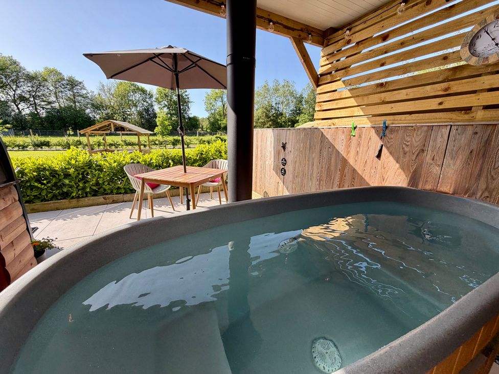 An outdoor area with a hot tub and a table with chairs at Oh Deer Ashbourne