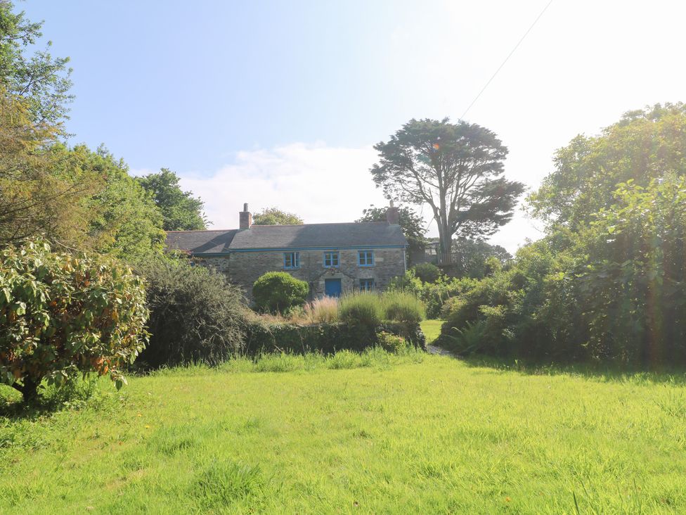 A house with blue windows and door surrounded by grass and garden at Sunnyvale Cottage in Rosudgeon