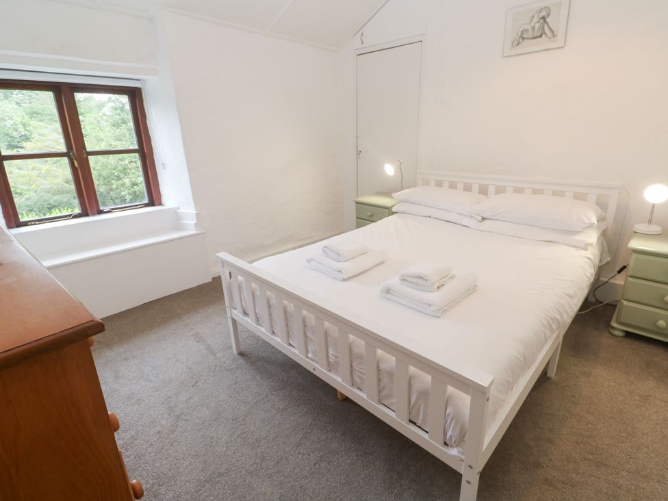 A bedroom with a bed, nightstands, and a window at Sunnyvale Cottage in Rosudgeon