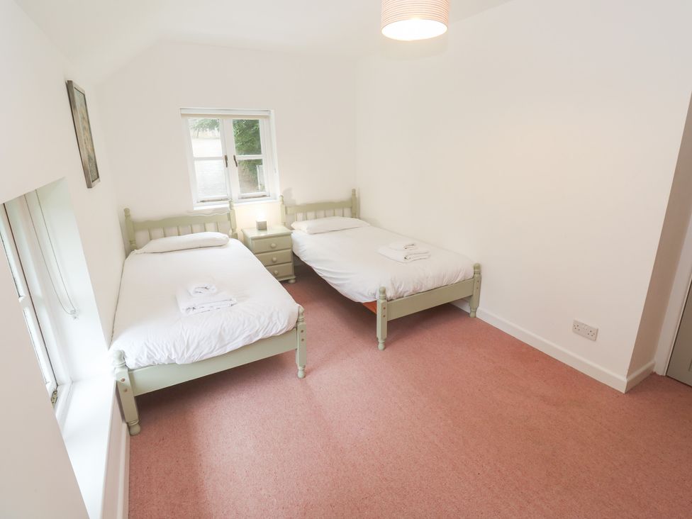 A bedroom with two beds and a bedside table at Sunnyvale Cottage in Rosudgeon