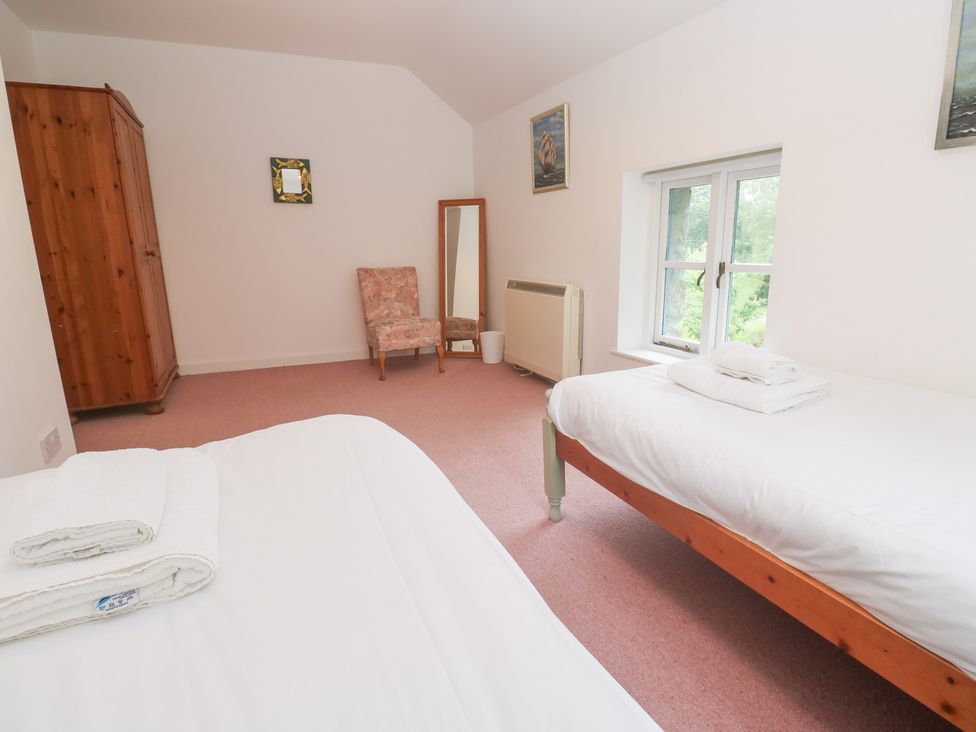 A bedroom with two beds and a wardrobe at Sunnyvale Cottage in Rosudgeon