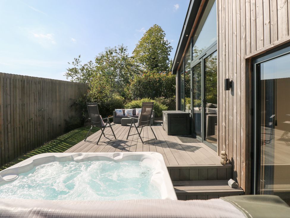 An outdoor area with a hot tub and seating at Cornerstones Brython in Tenby