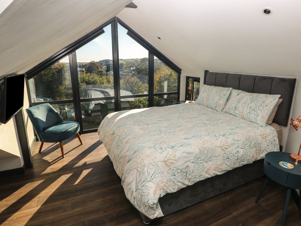 A bedroom with a bed and an armchair at 11 Brython Place in Tenby
