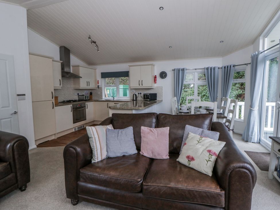 A living room with kitchen area and dining table at Seacroft in Stepaside near Kilgetty