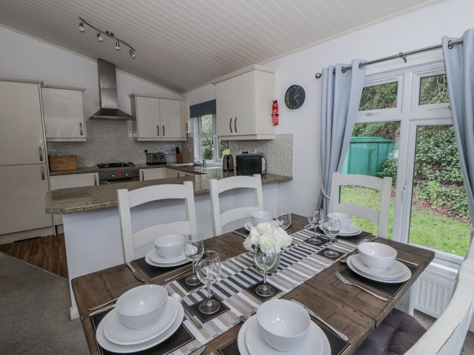 A kitchen and dining area with a table set for meals at Seacroft in Stepaside near Kilgetty