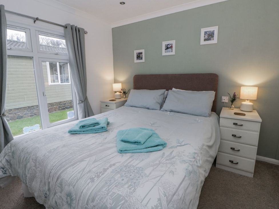 A bedroom with a double bed and bedside table at Seacroft near Kilgetty