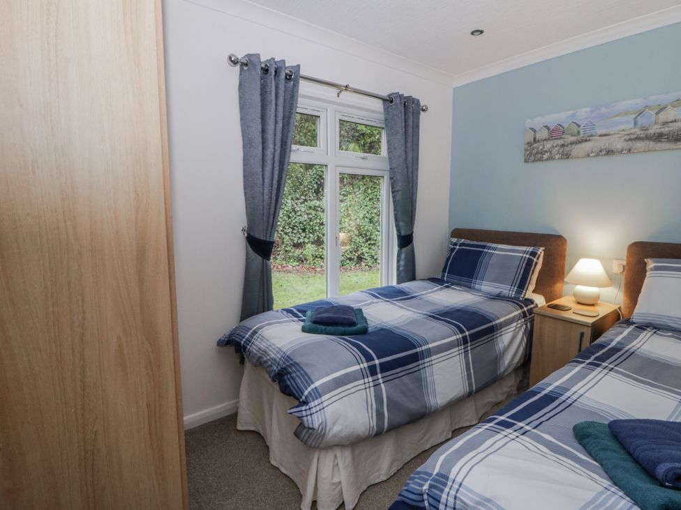 A bedroom with two beds and window at Seacroft in Stepaside near Kilgetty