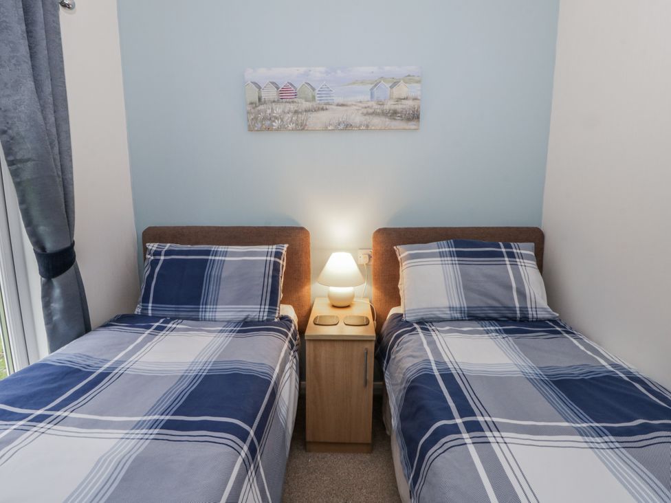 A bedroom with two beds and a nightstand at Seacroft in Stepaside near Kilgetty
