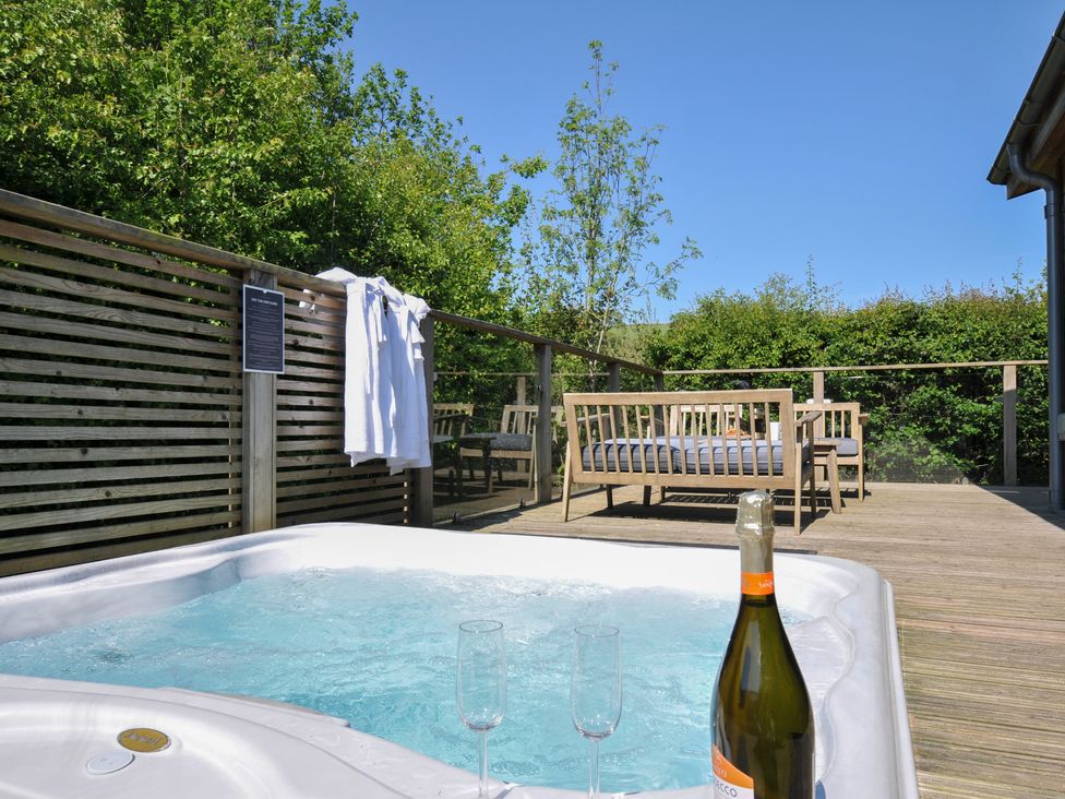 An outdoor terrace with a hot tub and seating at 7 Valley View in Lanreath