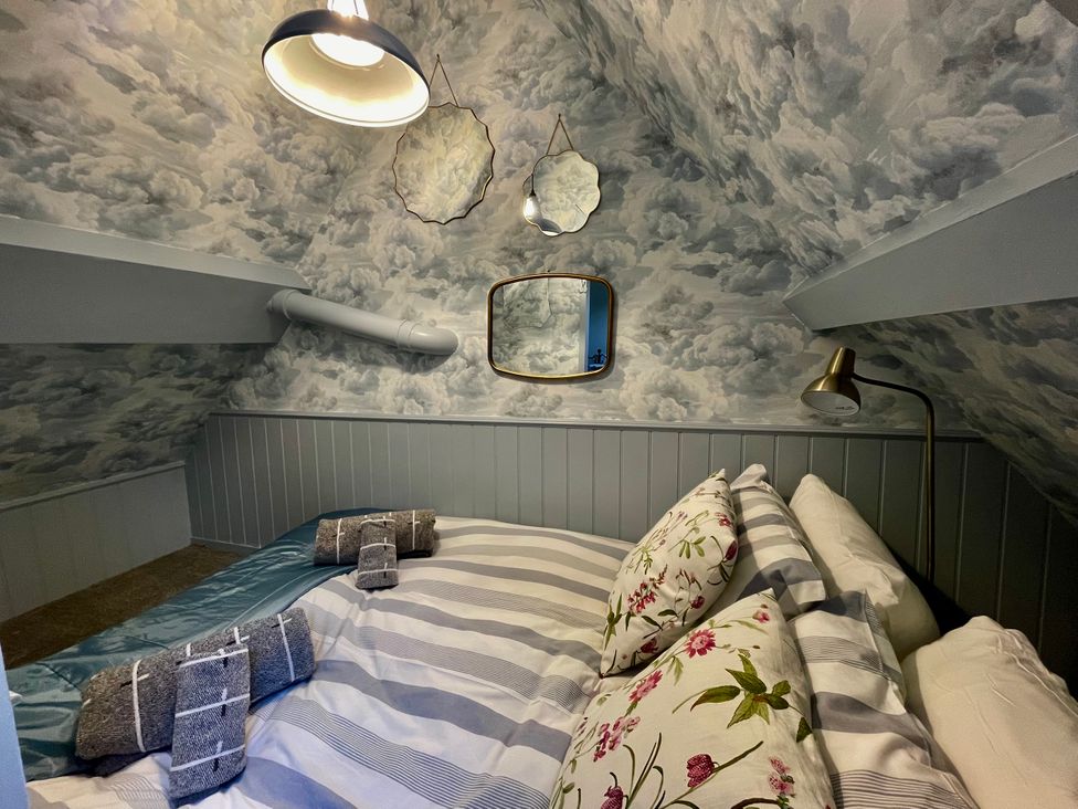 A bedroom with a bed, pillows, and mirrors at The Ticket Office in Ruswarp near Whitby