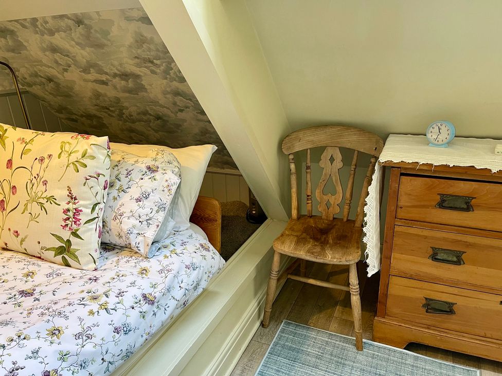 A bedroom with a bed and a wooden chair at The Ticket Office in Ruswarp near Whitby