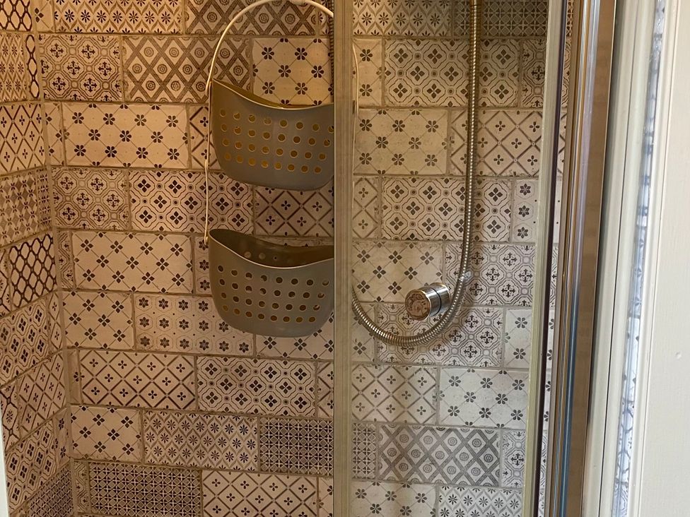 A shower with tiled walls and storage baskets at The Ticket Office in Ruswarp near Whitby