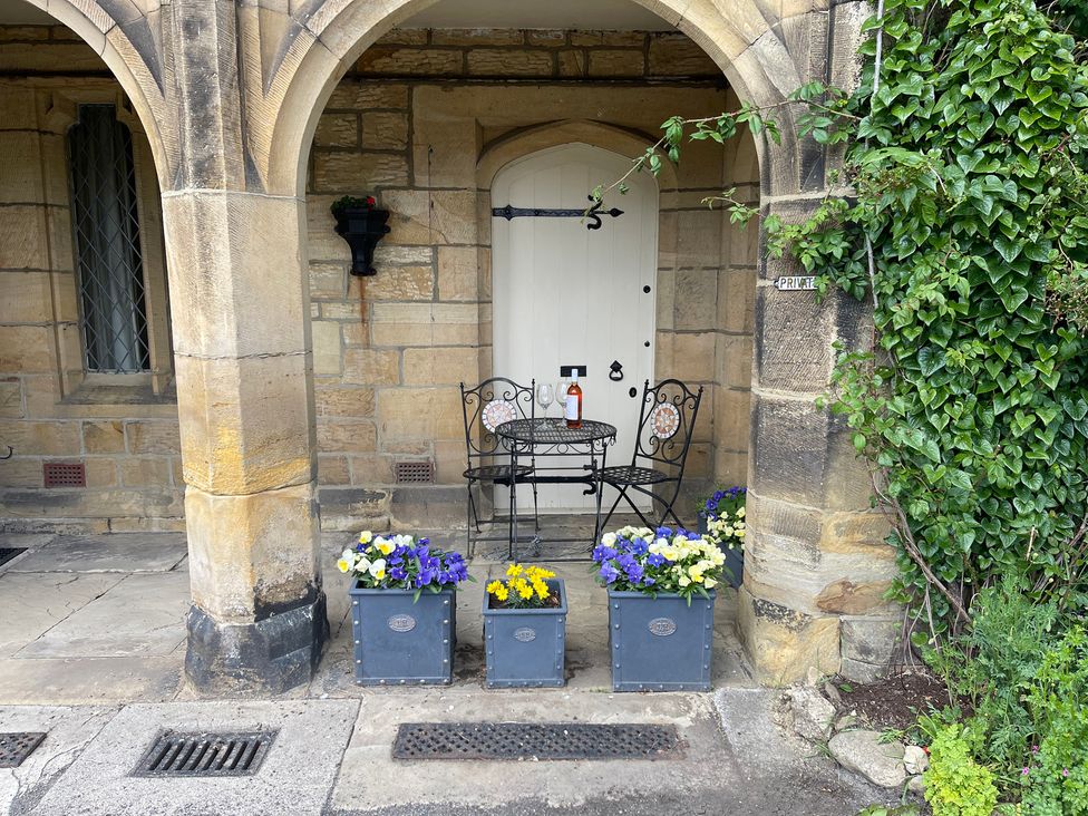 An outdoor area with a table and chairs in front of a door at The Ticket Office in Ruswarp near Whitby