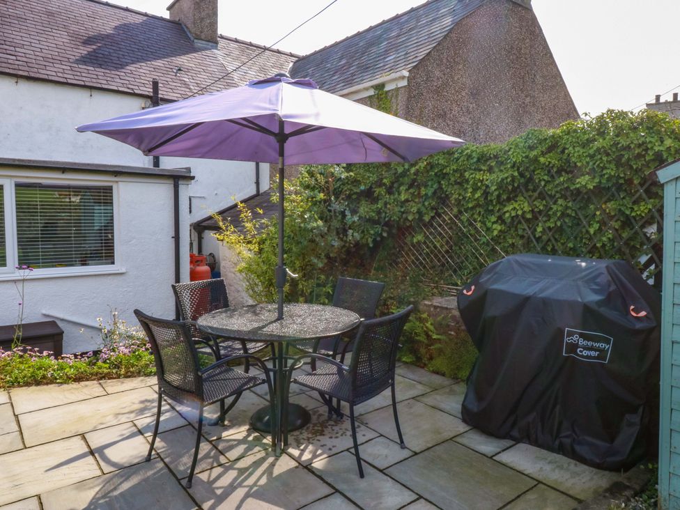 A garden with a table and chairs under an umbrella at Bryn Tirion in Moelfre
