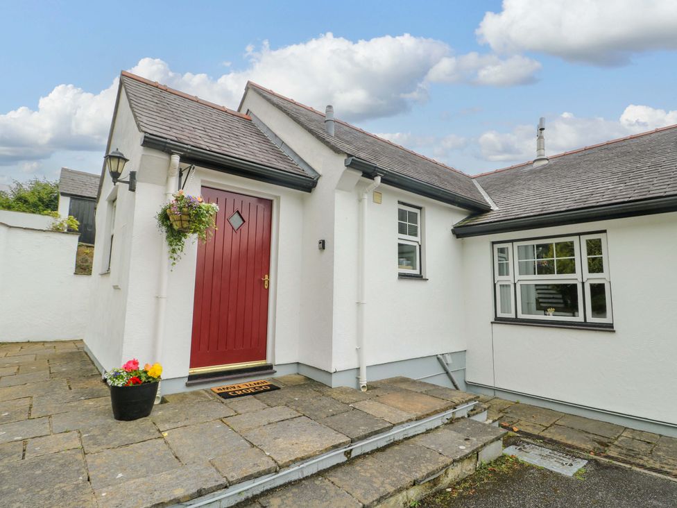 A house entrance with a red door and flower pots at Bwthyn Clai in Llangefni