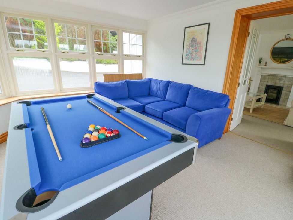 A snug with a pool table and blue couch at Bwthyn Clai in Llangefni