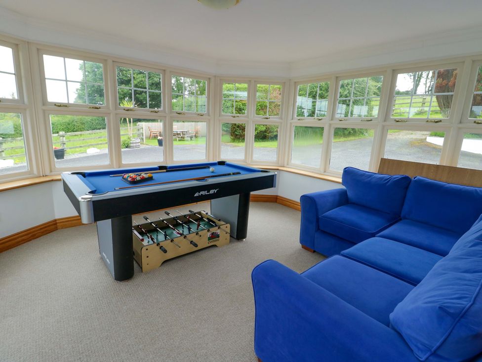 A snug room with a pool table and a blue sofa at Bwthyn Clai in Llangefni