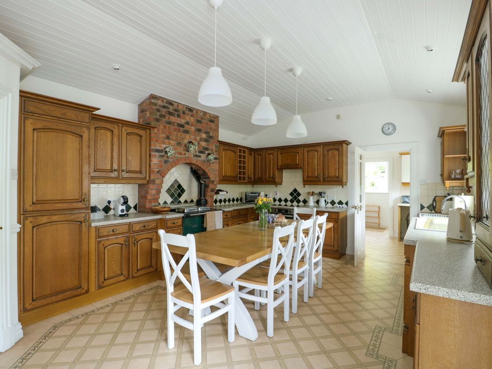 A kitchen with wooden cabinets and a large table at Bwthyn Clai in Llangefni