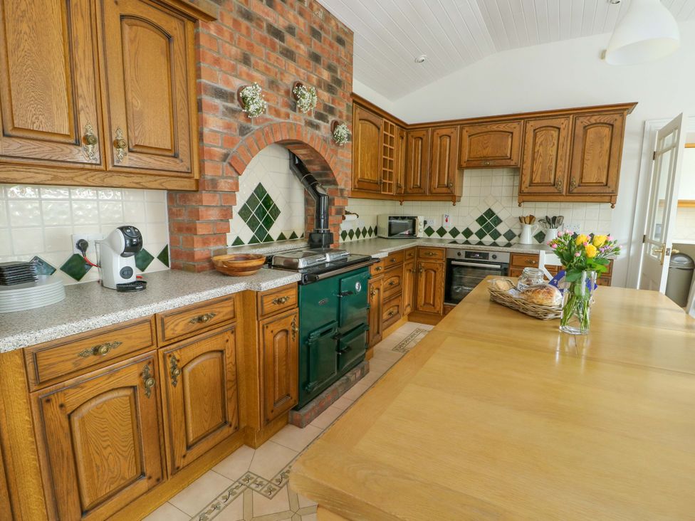 A kitchen with cabinets, oven, and coffee maker at Bwthyn Clai in Llangefni