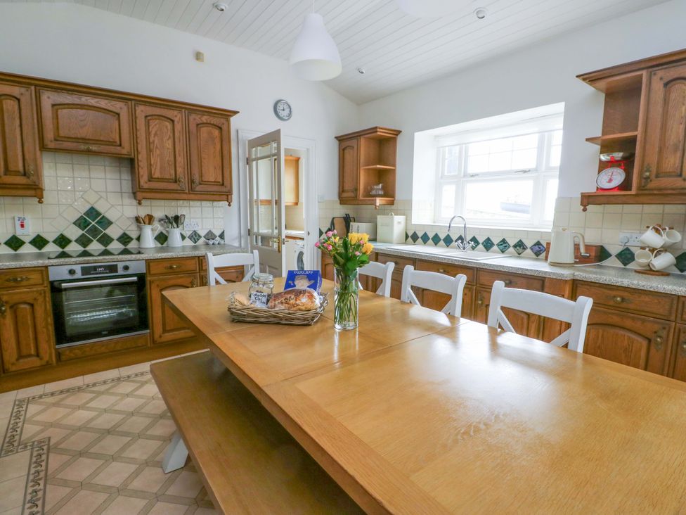 A kitchen with a wooden table and chairs at Bwthyn Clai in Llangefni