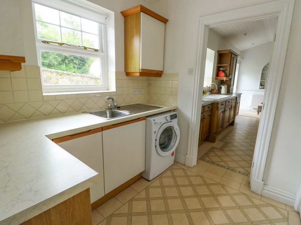 A kitchen with a sink and washing machine at Bwthyn Clai in Llangefni
