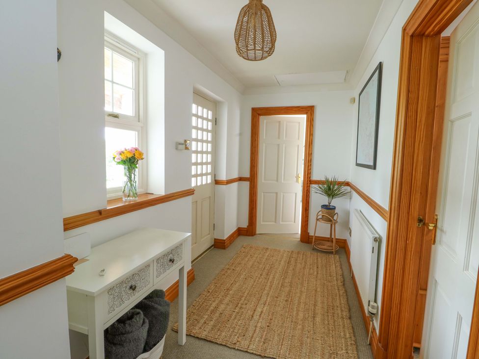 A hallway with a console table and rug at Bwthyn Clai in Llangefni